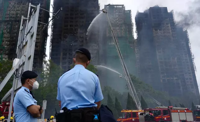 Police officers stand guard at the scene of a fire which broke out Wednesday at Wang Fuk Court, a residential estate in the Tai Po district of Hong Kong's New Territories, Thursday, Nov. 27, 2025. (AP Photo/Chan Long Hei)