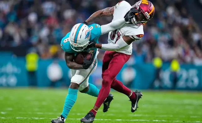 Washington Commanders cornerback Jonathan Jones (31) tackles Miami Dolphins wide receiver Malik Washington (6), left, during the first half of an NFL football game between the Washington Commanders and the Miami Dolphins in Madrid, Spain, Sunday, Nov. 16, 2025. (AP Photo/Manu Fernandez)