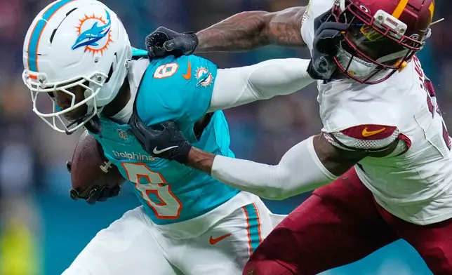 Washington Commanders cornerback Jonathan Jones (31) tackles Miami Dolphins wide receiver Malik Washington (6), left, during the first half of an NFL football game between the Washington Commanders and the Miami Dolphins in Madrid, Spain, Sunday, Nov. 16, 2025. (AP Photo/Manu Fernandez)