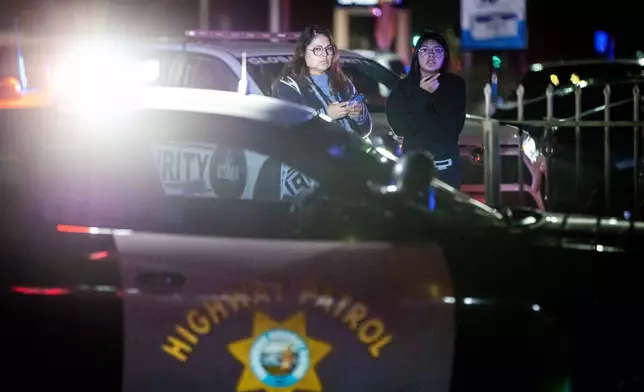 Bystanders watch at the scene of a mass shooting Saturday, Nov. 29, 2025, in Stockton, Calif. (AP Photo/Ethan Swope)