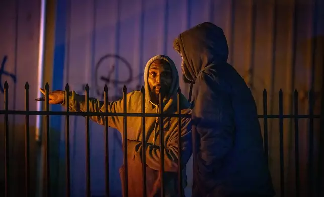 Bystanders watch at the scene of a mass shooting Saturday, Nov. 29, 2025, in Stockton, Calif. (AP Photo/Ethan Swope)