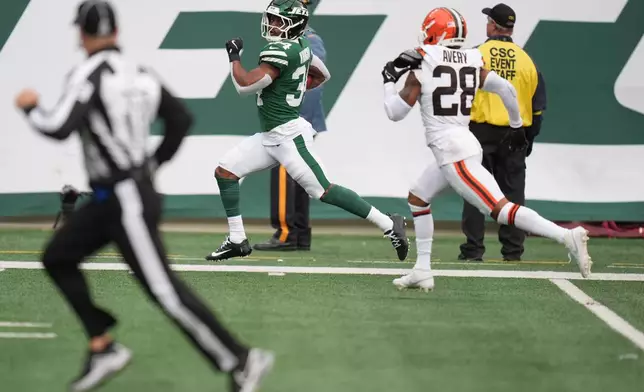New York Jets running back Kene Nwangwu (34) takes a kickoff return into the end zone for a touchdown in front of Cleveland Browns cornerback Tre Avery (28) in the first half of an NFL football game, Sunday, Nov. 9, 2025, in East Rutherford, N.J. (AP Photo/Seth Wenig)