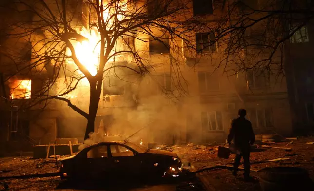 A man walks in front of burning residential building after a Russian attack on Zaporizhzhia, Ukraine, Wednesday, Nov. 26, 2025. (AP Photo/Kateryna Klochko)