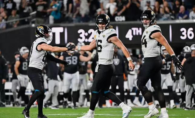 Jacksonville Jaguars quarterback Trevor Lawrence (16) celebrates with wide receiver Austin Trammell, left, after scoring a touchdown during overtime of an NFL football game against the Las Vegas Raiders, Sunday, Nov. 2, 2025, in Las Vegas. (AP Photo/David Becker)