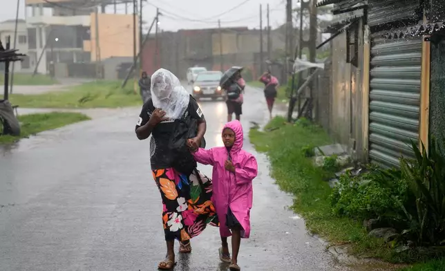 A woman and child walk under a downpour in Colombo, Sri Lanka, Friday, Nov. 28, 2025. (AP Photo/Eranga Jayawardena)