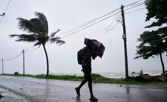 A man walks under a heavy downpour in Colombo, Sri Lanka, Friday, Nov. 28, 2025. (AP Photo/Eranga Jayawardena)