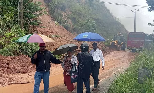 People walk past a section of a highway blocked by a landslide caused by heavy rain in Badulla, Sri Lanka, Thursday, Nov, 27, 2025. (AP Photo)
