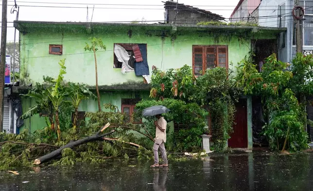 A tree is uprooted in front of a residential building partially damaged by heavy rains in Colombo, Sri Lanka, Friday, Nov. 28, 2025. (AP Photo/Eranga Jayawardena)