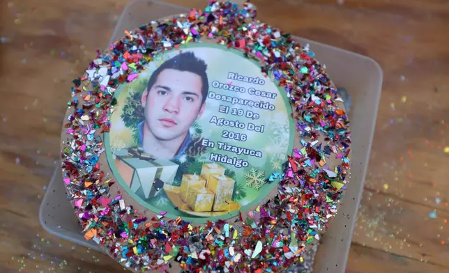 A photograph of Ricardo Orozco, who disappeared on August 19, 2016 in Tizayuca, Hidalgo state, decorates a Christmas ornament to hang on the Tree of Hope during an event organized by the diocese of Ecatepec at the Church of the Sacred Heart of San Cristobal in Ecatepec, State of Mexico, Monday, Nov. 17, 2025. (AP Photo/Ginnette Riquelme)