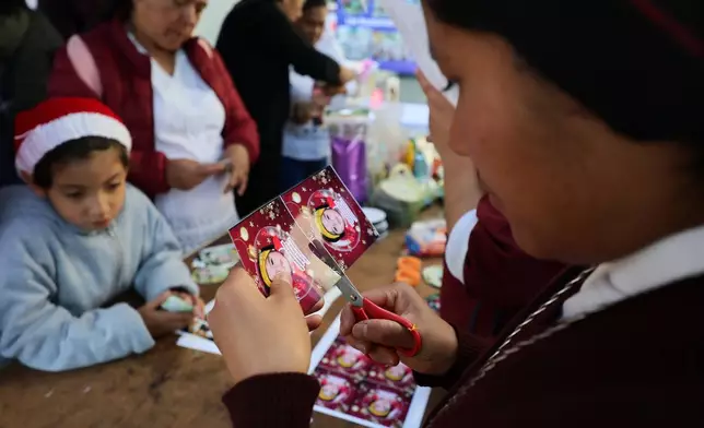 Sister Maria Elena cuts a photograph of a missing girl to paste on a Christmas ornament to hang on the Tree of Hope, during an event organized by the diocese of Ecatepec at the Church of the Sacred Heart of San Cristobal in Ecatepec, State of Mexico, Monday, Nov. 17, 2025. (AP Photo/Ginnette Riquelme)