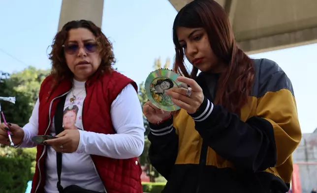 Marisol Rizo, left, who said her mother Maria Dolores Rizo Juarez went missing on Dec. 22, 2012 in Alcoman, state of Mexico, and her daughter Leslie Mendez, decorate Christmas ornaments with her photograph to hang on the Tree of Hope during an event organized by the diocese of Ecatepec at the Church of the Sacred Heart of San Cristobal in Ecatepec, State of Mexico, Monday, Nov. 17, 2025. (AP Photo/Ginnette Riquelme)