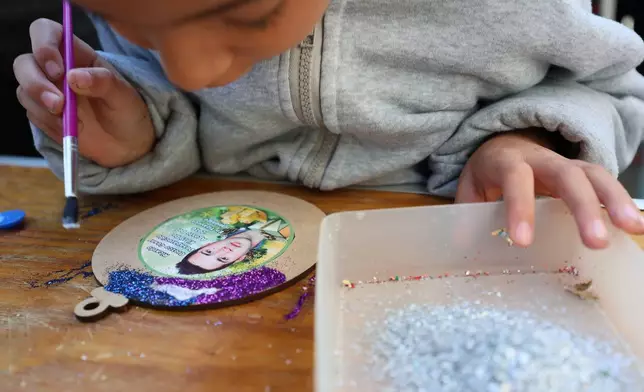 Arlet Guerra Orozco, 7, decorates a Christmas ornament with the image of his uncle Ricardo who went missing to hang on the Tree of Hope during an event organized by the diocese of Ecatepec at the Church of the Sacred Heart of San Cristobal in Ecatepec, State of Mexico, Monday, Nov. 17, 2025. (AP Photo/Ginnette Riquelme)
