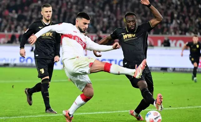 Augsburg's Chrislain Matsima, right, and Stuttgart's Deniz Undav, left, challenge for the ball during the German Bundesliga soccer match between VfB Stuttgart and FC Augsburg in Stuttgart, Germany, Sunday, Nov. 9, 2025. (Bernd Weissbrod/dpa via AP)