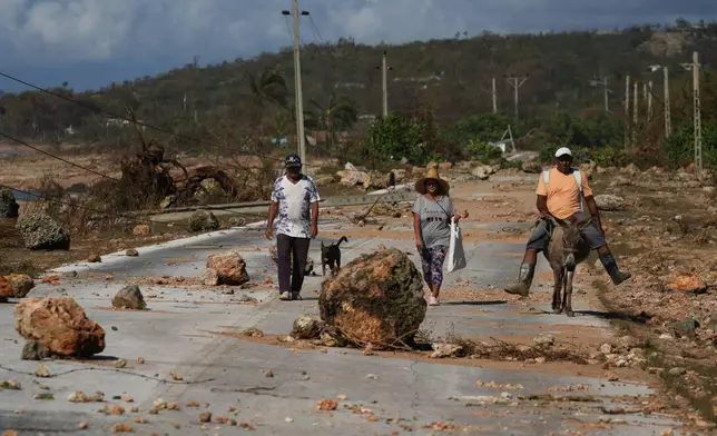 People traverse debris on a road after Hurricane Melissa passed through Santiago de Cuba, Thursday, Oct. 30, 2025. (AP Photo/Ramon Espinosa)
