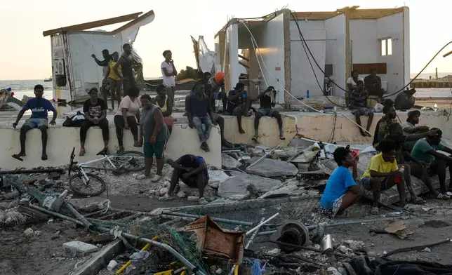 People gather among debris near a bridge in Black River, Jamaica, Thursday, Oct. 30, 2025, in the aftermath of Hurricane Melissa. (AP Photo/Matias Delacroix)