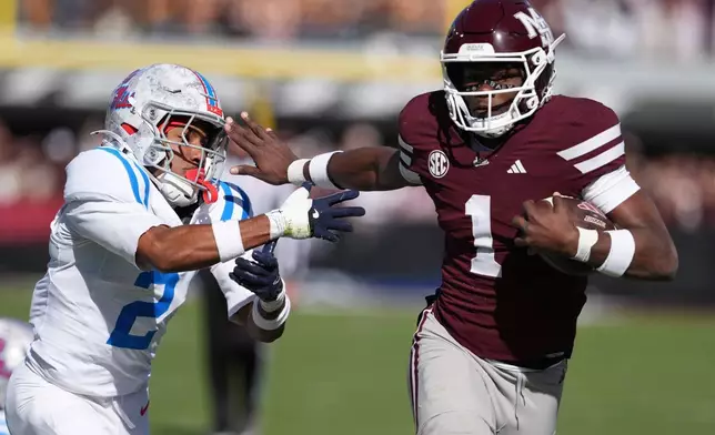 Mississippi State quarterback Kamario Taylor (1) stiff arms Mississippi cornerback Jaylon Braxton (2) as he runs for 22-yard touchdown during the first half of an NCAA college football game Frifday, Nov. 28, 2025, in Starkville, Miss. (AP Photo/Rogelio V. Solis)