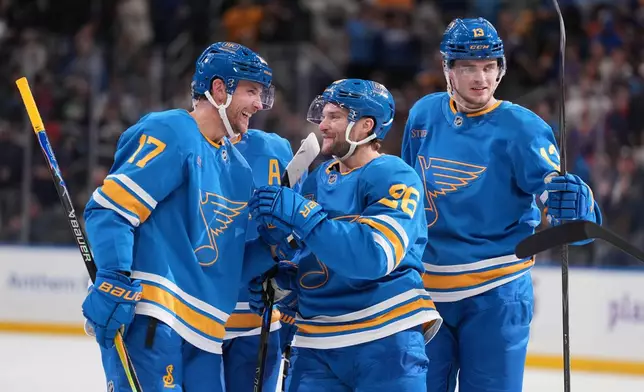 St. Louis Blues' Cam Fowler (17) is congratulated by teammate Nathan Walker, center, as Alexey Toropchenko (13) stands by after Fowler earned his 500th career point on an assist during the second period of an NHL hockey game against the Philadelphia Flyers Friday, Nov. 14, 2025, in St. Louis. (AP Photo/Jeff Roberson)