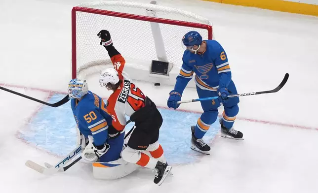 Philadelphia Flyers' Trevor Zegras (46) scores past St. Louis Blues' Philip Broberg (6) and goaltender Jordan Binnington (50) during the second period of an NHL hockey game Friday, Nov. 14, 2025, in St. Louis. (AP Photo/Jeff Roberson)