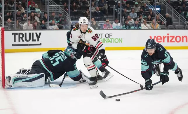 Chicago Blackhawks left wing Tyler Bertuzzi tries to score as Seattle Kraken defenseman Brandon Montour (62) blocks a pass and goalie Joey Daccord (35) defends during the second period of an NHL hockey game Monday, Nov. 3, 2025, in Seattle. (AP Photo/Jason Redmond)