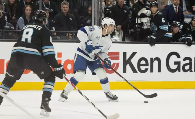 Tampa Bay Lightning left wing Brandon Hagel (38) moves the puck against Utah Mammoth right wing Nick Schmaltz (8) during the first period of an NHL hockey game Sunday, Nov. 2, 2025, in Salt Lake City. (AP Photo/Melissa Majchrzak)