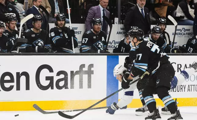 Tampa Bay Lightning center Dominic James (17) fights for the puck against Utah Mammoth right wing JJ Peterka (77) and defenseman Nate Schmidt, center, during the first period of an NHL hockey game Sunday, Nov. 2, 2025, in Salt Lake City. (AP Photo/Melissa Majchrzak)