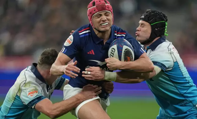 FILE -France's Louis Bielle-Biarrey, center, is tackled by Scotland's Darcy Graham, right, during the Six Nations rugby union match between France and Scotland at the Stade de France in Saint-Denis, outside Paris, March 15, 2025. (AP Photo/Christophe Ena, File)