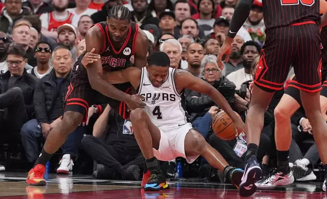 San Antonio Spurs guard De'Aaron Fox (4) battles for a loose ball against Chicago Bulls forward Patrick Williams during the first half of an NBA basketball game in Chicago, Monday, Nov. 10, 2025. (AP Photo/Nam Y. Huh)