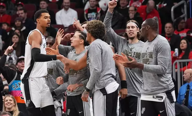 San Antonio Spurs forward Victor Wembanyama, left, celebrates with teammates after scoring a basket during the first half of an NBA basketball game against the Chicago Bulls in Chicago, Monday, Nov. 10, 2025. (AP Photo/Nam Y. Huh)