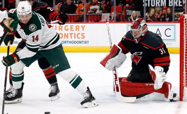 Minnesota Wild's Joel Eriksson Ek (14) tries to backhand the puck at Carolina Hurricanes goaltender Frederik Andersen (31) during the first period of an NHL hockey game in Raleigh, N.C., Thursday, Nov. 6, 2025. (AP Photo/Karl DeBlaker)
