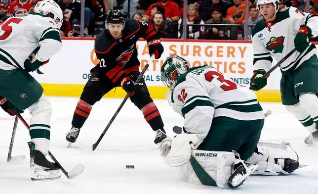 Carolina Hurricanes' Logan Stankoven (22) controls the puck in front of Minnesota Wild goaltender Filip Gustavsson (32) during the second period of an NHL hockey game, in Raleigh, N.C., Thursday, Nov. 6, 2025. (AP Photo/Karl DeBlaker)