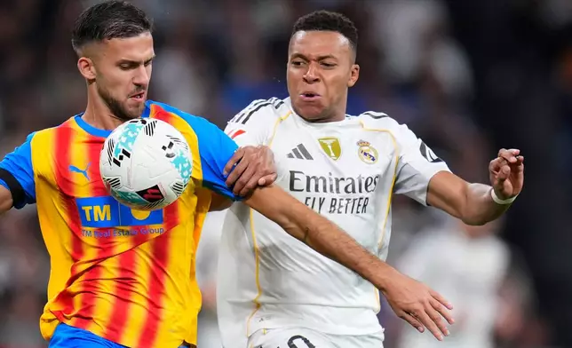 Real Madrid's Kylian Mbappe, right, and Valencia's Jose Copete challenge for the ball during the Spanish La Liga soccer match between Real Madrid and Valencia in Madrid, Spain, Saturday, Nov. 1, 2025. (AP Photo/Manu Fernandez)