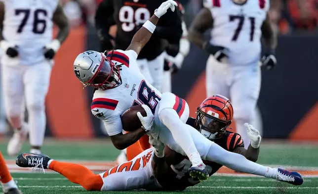 New England Patriots wide receiver Kyle Williams (18) is tackled by Cincinnati Bengals linebacker Barrett Carter during the second half of an NFL football game, Sunday, Nov. 23, 2025, in Cincinnati. (AP Photo/Carolyn Kaster)