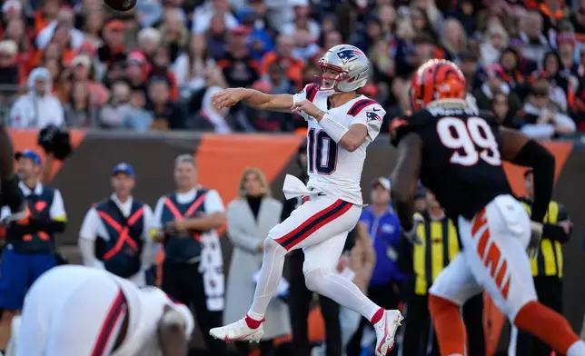 New England Patriots quarterback Drake Maye (10) throws a pass ahead of Cincinnati Bengals defensive end Myles Murphy (99) during the second half of an NFL football game, Sunday, Nov. 23, 2025, in Cincinnati. (AP Photo/Carolyn Kaster)