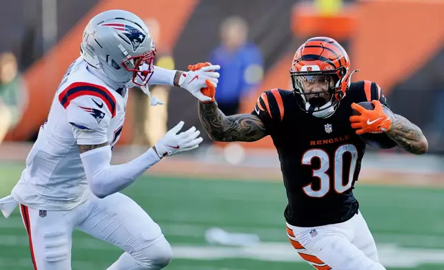 Cincinnati Bengals running back Chase Brown (30) runs from New England Patriots cornerback Carlton Davis III (7) during the first half of an NFL football game, Sunday, Nov. 23, 2025, in Cincinnati. (AP Photo/Jay LaPrete)