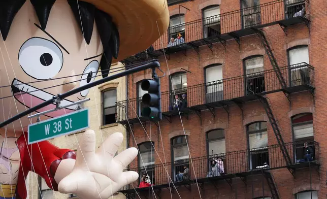 People watch from their balconies as the Monkey D. Luffy balloon passes them during the Macy's Thanksgiving Day Parade, Thursday, Nov. 27, 2025, in New York. (AP Photo/Heather Khalifa)