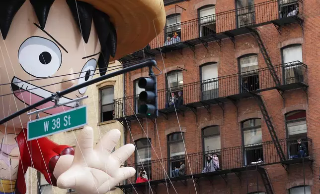People watch from their balconies as the Monkey D. Luffy balloon passes them during the Macy's Thanksgiving Day Parade, Thursday, Nov. 27, 2025, in New York. (AP Photo/Heather Khalifa)