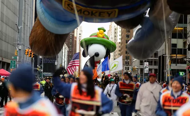 The Beagle Scout Snoopy balloon floats down Sixth Avenue led by the Smokey the Bear balloon during the Macy's Thanksgiving Day Parade, Thursday, Nov. 27, 2025, in New York. (AP Photo/Eduardo Munoz Alvarez)