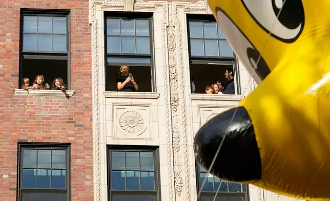 Spectators watch from their apartment windows as the Goldbear balloon floats by during the Macy's Thanksgiving Day Parade, Thursday, Nov. 27, 2025, in New York. (AP Photo/Frank Franklin)