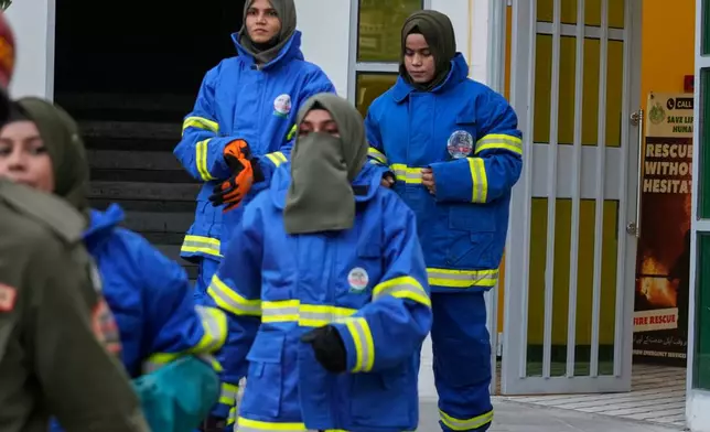 Female firefighter Syeda Masooma Zaidi, right back, arrives with her team members to attend a routine training session, at the compound of their office in Karachi, Pakistan, Friday, Oct. 10, 2025. (AP Photo/Fareed Khan)