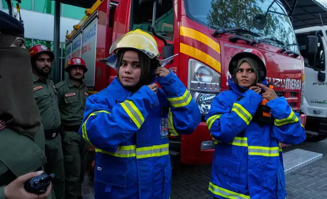 Female firefighter Syeda Masooma Zaidi, center, prepares with her team members to attend a routine training session, at the compound of their office in Karachi, Pakistan, Friday, Oct. 10, 2025. (AP Photo/Fareed Khan)