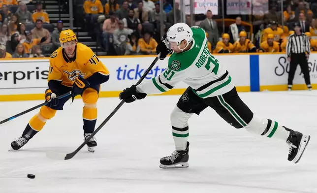Dallas Stars left wing Jason Robertson (21) gets a shot away as he is defended by Nashville Predators right wing Michael McCarron (47) during the first period of an NHL hockey game Saturday, Nov. 8, 2025, in Nashville, Tenn. (AP Photo/Mark Humphrey)