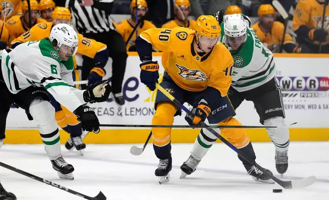 Nashville Predators center Fedor Svechkov (40) moves the puck ahead of Dallas Stars defenders Lian Bichsel (6) and Radek Faksa (12) during the second period of an NHL hockey game Saturday, Nov. 8, 2025, in Nashville, Tenn. (AP Photo/Mark Humphrey)
