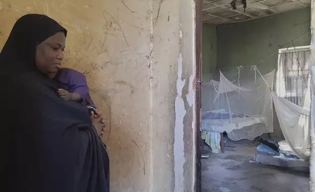 Amina Hassan, wife of the vice principal of the Government Girls Comprehensive Secondary School, where gunmen on Monday attacked the school dormitory, abducted schoolgirls and killed her husband, stands in front of the room where he was killed, in Kebbi, Nigeria, Tuesday, Nov. 18, 2025. (AP Photo/Tunde Omolehin)
