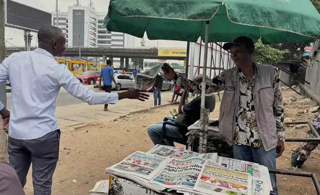 A vendor display local newspapers on the street of Lagos with headlines of the Government Girls Comprehensive Secondary School, where gunmen on Monday attacked the school dormitory, abducted schoolgirls, in Kebbi Nigeria, Wednesday, Nov. 19 2025. (AP Photo/Sunday Alamba )