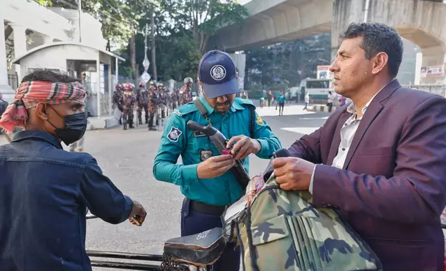 A police man checks the bag of a commuter near International Crimes Tribunal after security has been beefed up across the country ahead of an expected verdict against ousted Prime Minister Sheikh Hasina, in Dhaka, Bangladesh, Monday, Nov. 17, 2025. (AP Photo/Rajib Dhar)