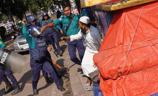Police use baton to disperse protesters gather outside the demolished residence of Sheikh Mujibur Rahman, Bangladesh's former leader and the father of the country's ousted Prime Minister Sheikh Hasina ahead of an expected verdict against Hasina, in Dhaka, Bangladesh, Monday, Nov. 17, 2025. (AP Photo/ Ahadul Karim Khan)