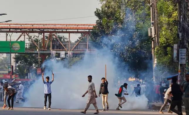 Protesters throw stones and shout slogans during a standoff with police outside the demolished residence of Sheikh Mujibur Rahman, Bangladesh's former leader and the father of the country's ousted Prime Minister Sheikh Hasina after the verdict against Hasina, in Dhaka, Bangladesh, Monday, Nov. 17, 2025. (AP Photo/ Rajib Dhar)
