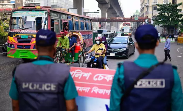Security personnel stand guard at a traffic intersection as ousted Prime Minister Sheikh Hasina and her former ruling Awami League party called for a nationwide "lockdown" in protest against her trial, in Dhaka, Bangladesh, Thursday, Nov. 13, 2025. (AP Photo/Mahmud Hossain Opu)