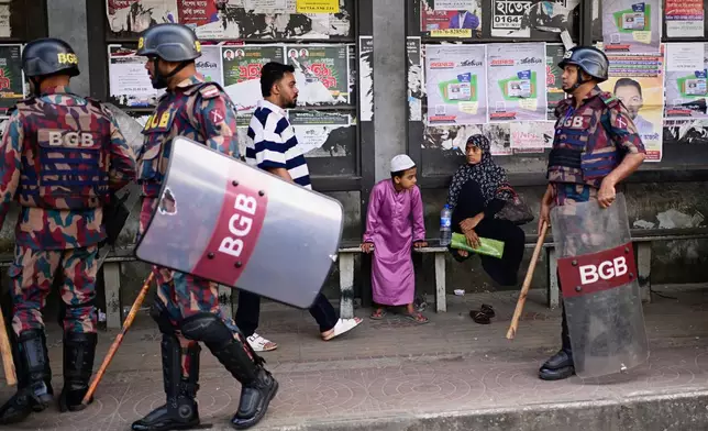 Security personnel walk past a bus stop as ousted Prime Minister Sheikh Hasina and her former ruling Awami League party called for a nationwide "lockdown" in protest against her trial, in Dhaka, Bangladesh, Thursday, Nov. 13, 2025. (AP Photo/Mahmud Hossain Opu)