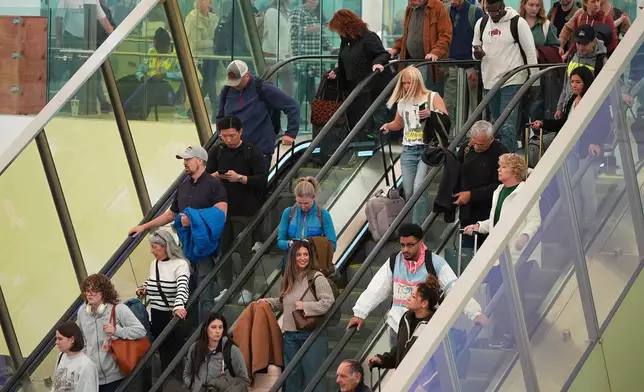 Travellers head tdown an escalator after clearing through a security checkpoint in Denver International Airport Friday, Nov. 7, 2025, in Denver. (AP Photo/David Zalubowski)